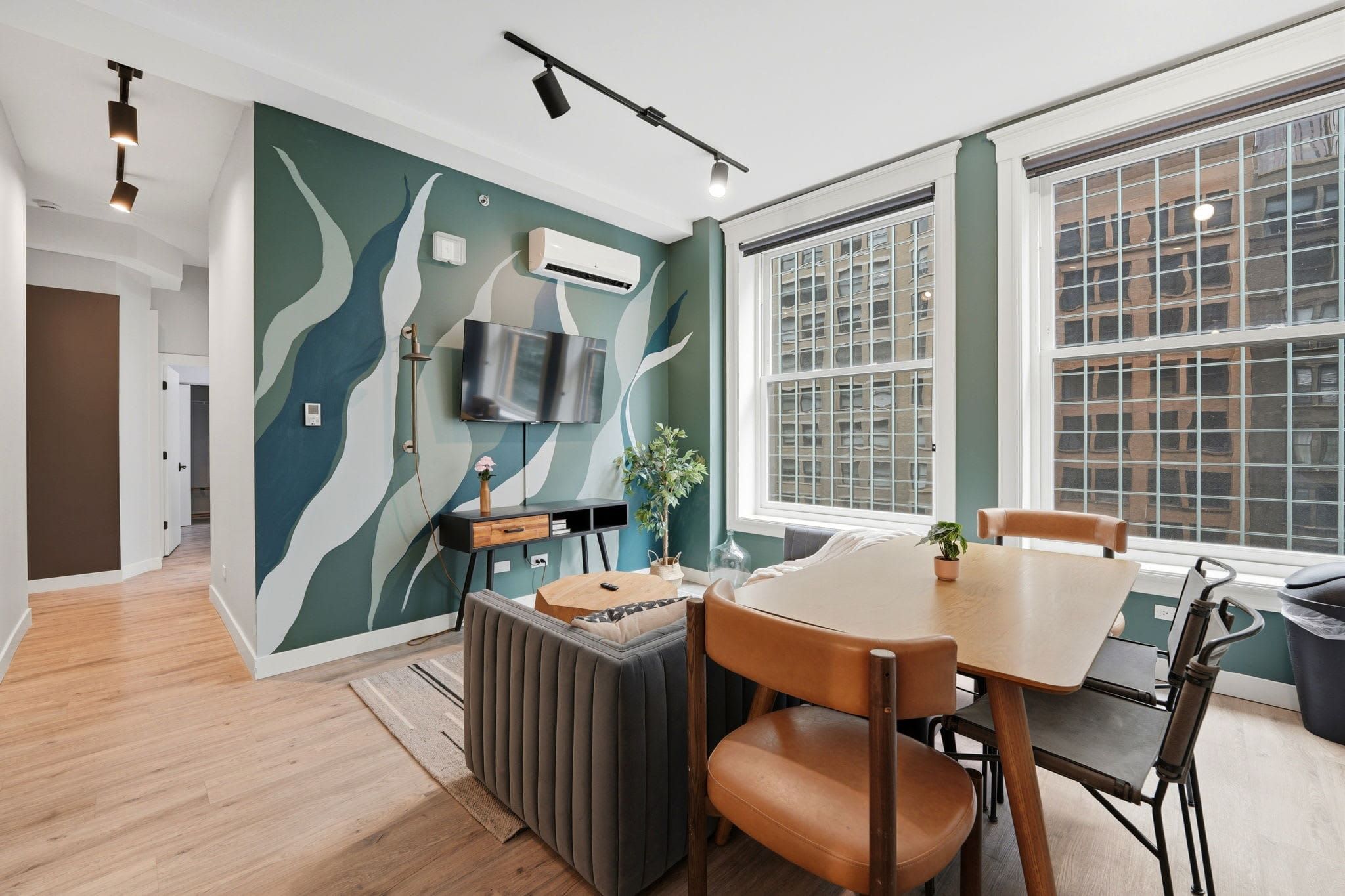 Four-bedroom suite dining area with a teal mural wall and warm leather chairs
