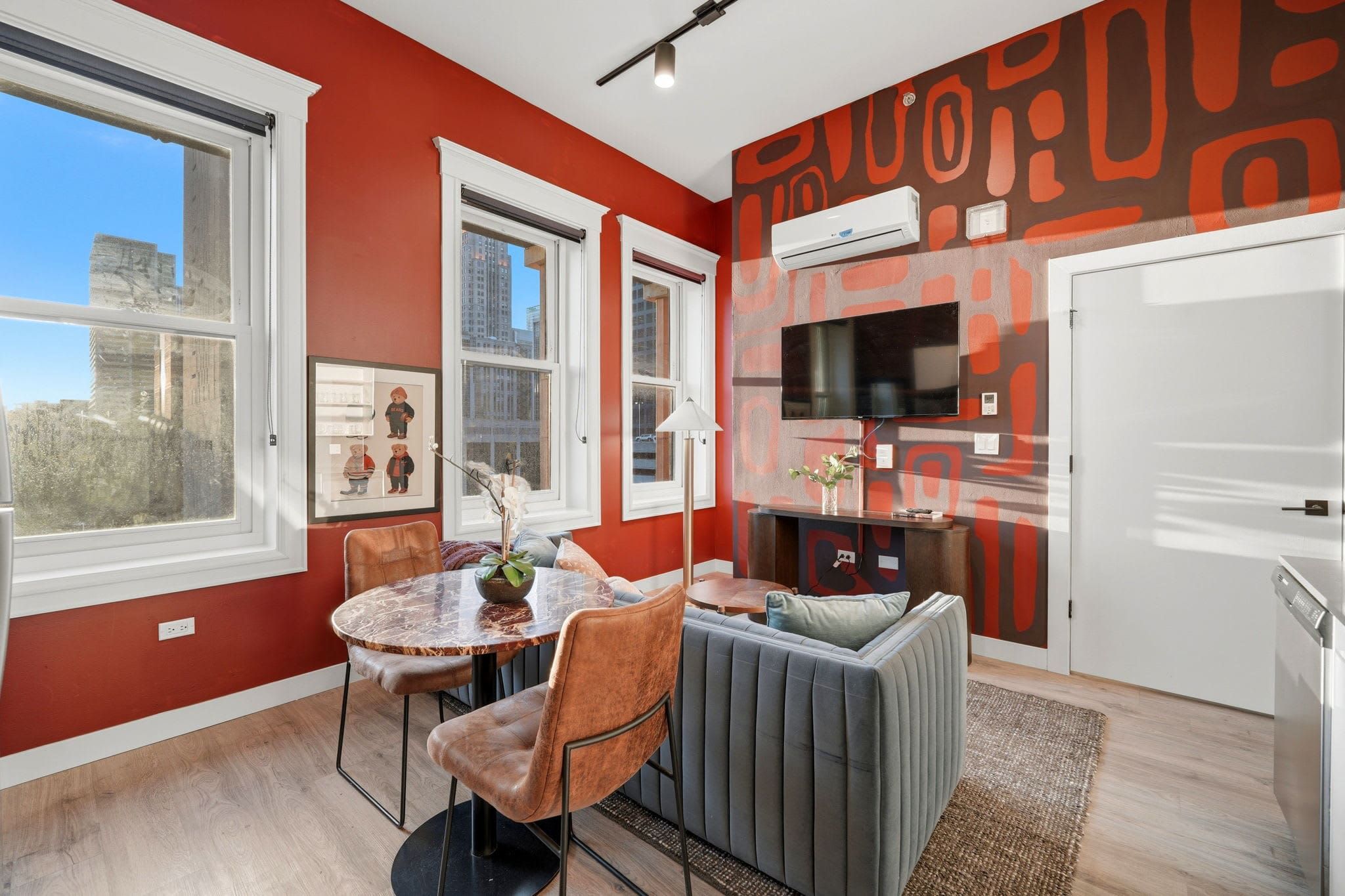 Two-bedroom suite living area with a navy mural wall, mounted TV, and city-view windows