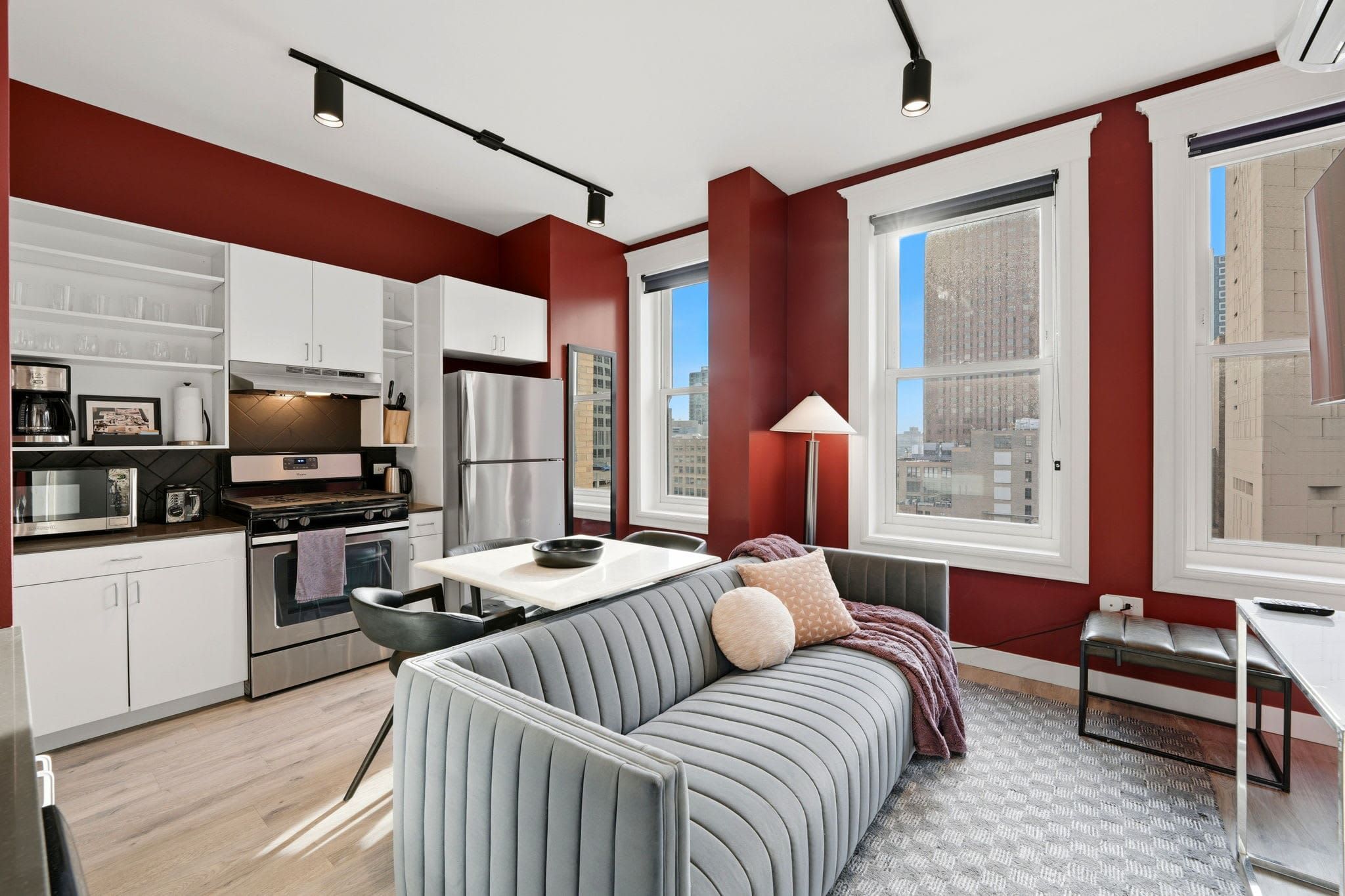 Top-floor two-bedroom suite living and kitchen area with deep red walls and bright skyline windows