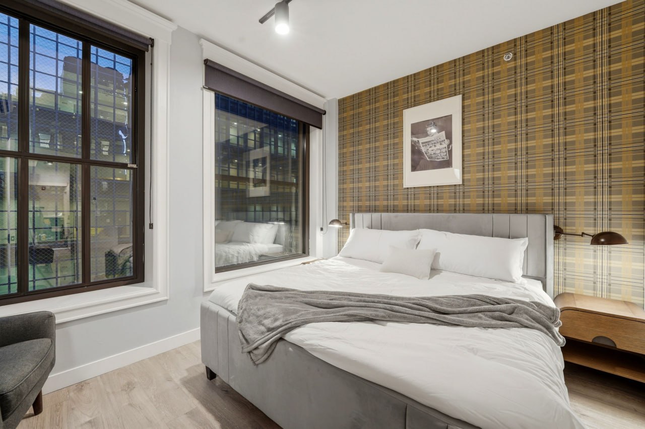 Bedroom with a plaid wallpaper wall, an upholstered bed, and tall windows