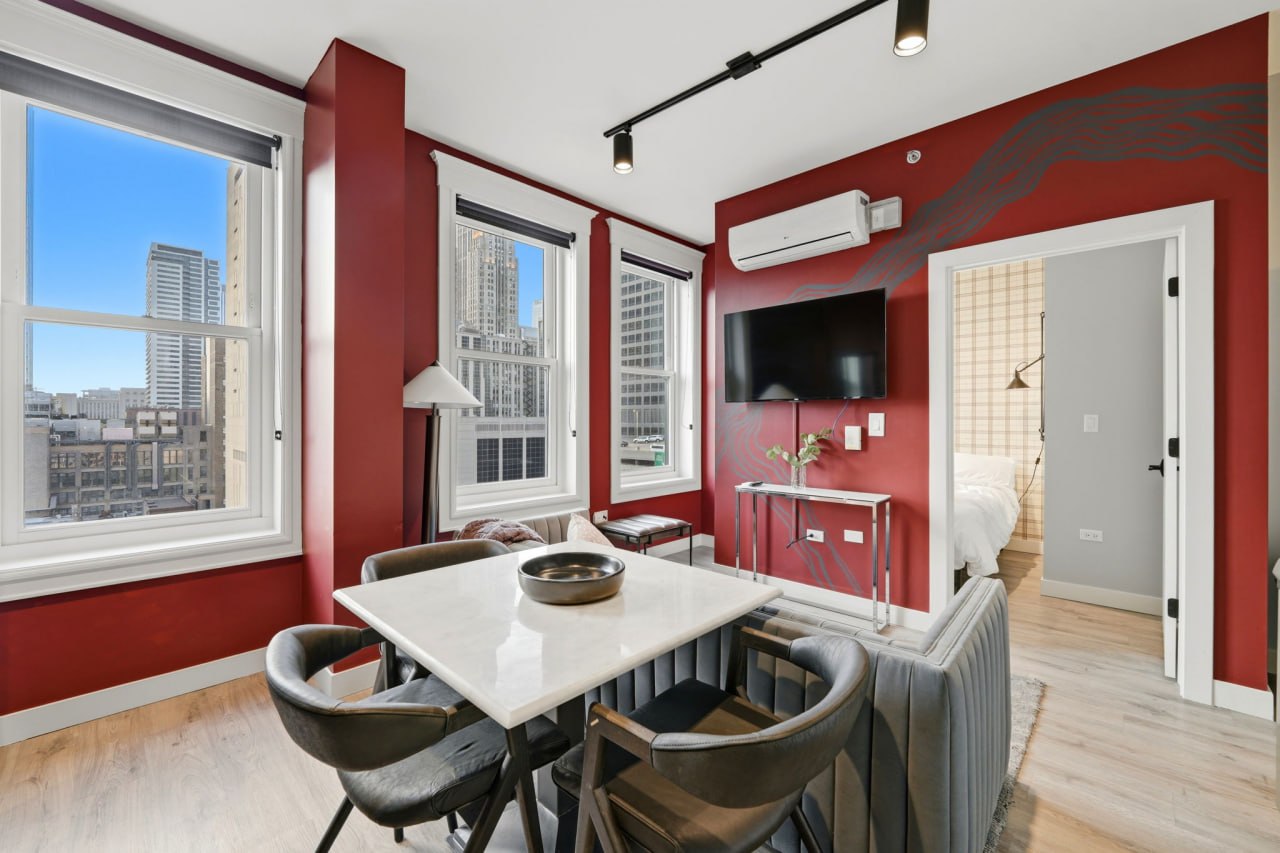 Red-walled dining room with a marble table and dark chairs beside tall windows